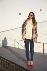 Un classico look invernale: maglione di lana a trecce e maxi sciarpa tartan 